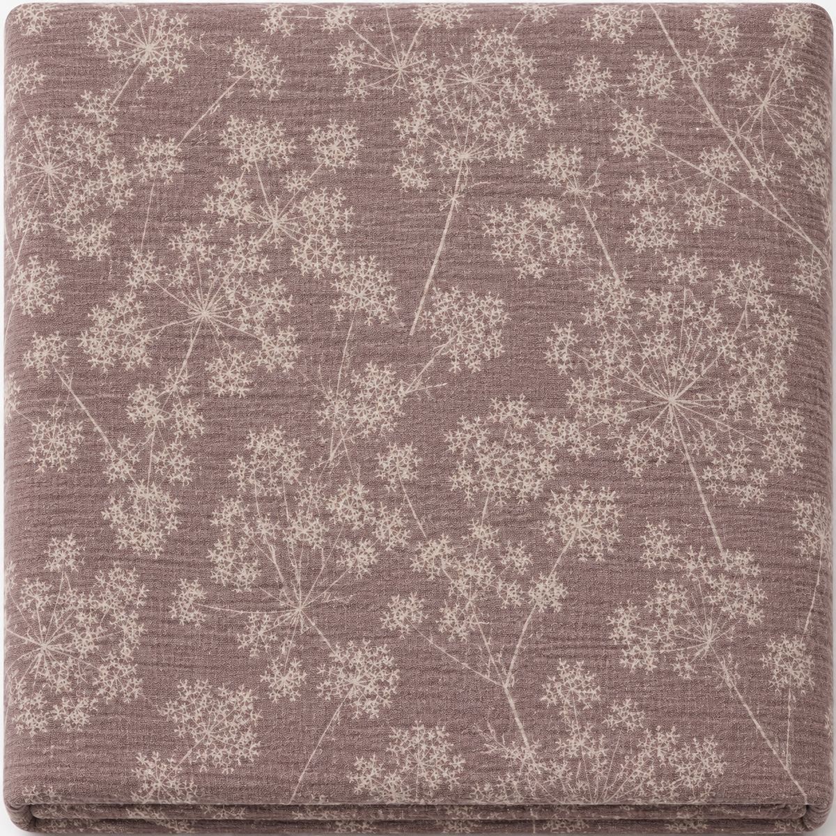 A folded piece of textured cotton muslin fabric with a delicate white dandelion and wildflower pattern on a dusty mauve-brown background.