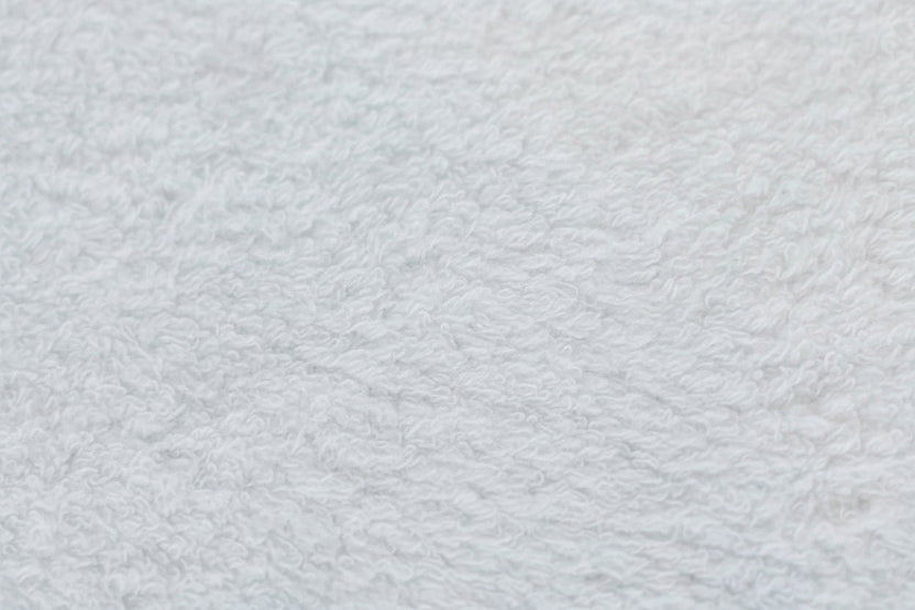 A close-up view of a white textured fabric, showing a soft, fuzzy, or plush material surface.