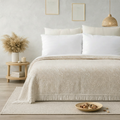 Neatly made bed with beige blanket and white pillows in a bedroom setting.